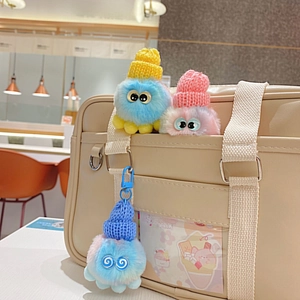 Bunter Plüsch-Oktopus-Anhänger mit Strickmütze an beiger Tragetasche im Café