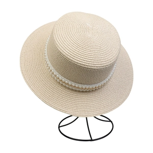 Detailed view of beige straw sun hat featuring elegant double-row pearl and chain trim