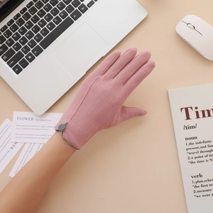 Detail of pink thermal gloves for women with houndstooth buckle on a desk setup
