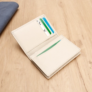 Detail of cream leather business card holder with multiple card slots on wooden surface