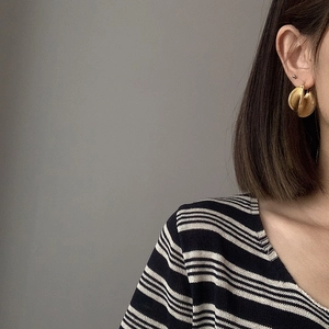 Close-up of gold-plated geometric earrings with brushed metal texture and layered design