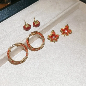 Close-up of maple leaf and persimmon earrings set in a jewelry display tray