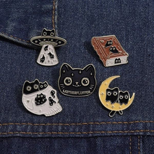 Detailed view of five creative black cat enamel pins pinned on blue denim fabric texture