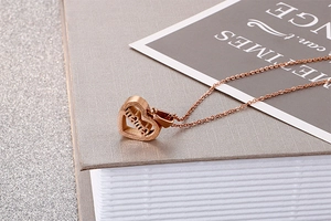 Macro detail of rose gold heart-shaped mama pendant necklace with smooth metallic texture