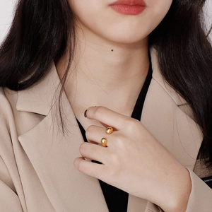 Chic gold-plated sphere open ring shown on model wearing a modern beige blazer