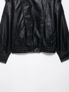 Detail of black faux leather jacket showing textured grain and elasticated hemline