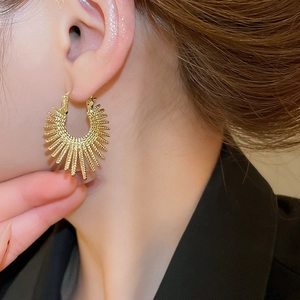 Close-up of golden sunburst textured hoop earrings featuring a vintage metallic finish