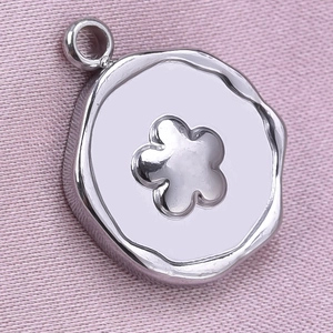 Macro shot of a silver 304 stainless steel round pendant with a hollow flower cutout design