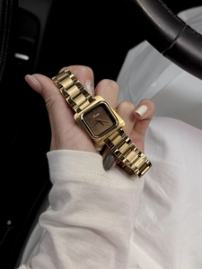 Gros plan d'une montre carrée vintage avec bracelet en métal doré et cadran chocolat
