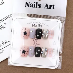 Handmade pink and black checkered press-on nails with silver stars and rhinestones