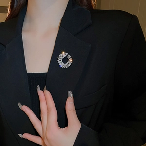 Close-up of a silver leaf wreath brooch with marquise crystals on a black suit lapel