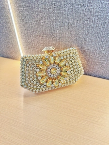 Detail van zonnebloemkristalpatronen en glinsterende strassteentjes op een gouden clutch