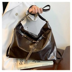 Detail of the high-shine faux leather texture and golden metal buckle on a tote bag