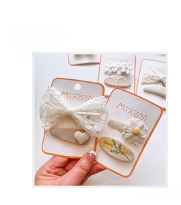 Detail view of lace bow and flower embroidery hair clips in warm matcha and cream colors