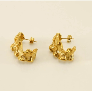 Detailed close-up of C-shaped 18k gold earrings with textured wavy pleated finish