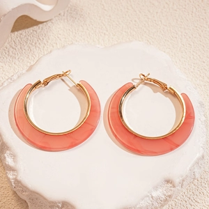 Close-up of C-shaped pink acetate hoops with marble texture and gold metallic borders