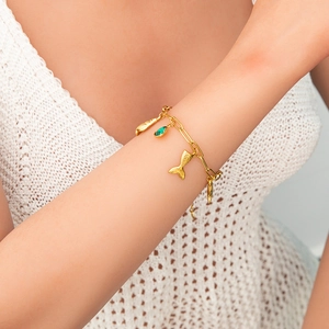 Detail of 18K gold plated bracelet featuring green drop gemstone and sea-themed charms
