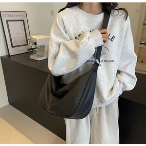 Close-up of black nylon half-moon crossbody bag shown in a stylish cafe lifestyle setting