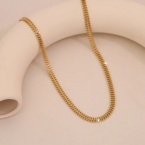 Detail of gold wheat chain necklace featuring intricate braided metal textures and glossy finish