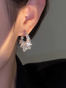 Close-up detail of silver bird nest hollow earrings worn by a model in warm lighting