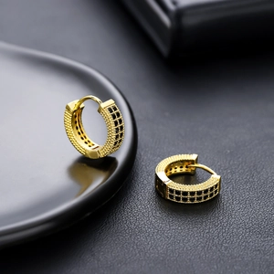 Détail macro de boucles d'oreilles créoles dorées serties de zircons noirs pavés