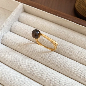 Detailed view of vintage gold ring featuring a brown tiger eye bead and smooth metal bar
