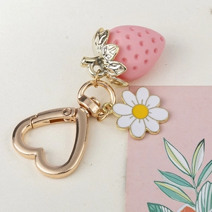 Close-up of strawberry keychain with daisy charm and heart-shaped golden clasp
