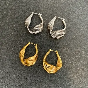 Detailed macro view of gold and silver chunky twisted hoop earrings with ribbed texture