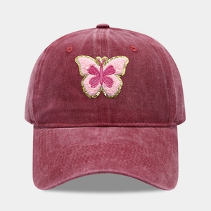 Détail d'une casquette bordeaux avec broderie papillon rose et paillettes dorées