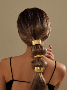 Three gold metal hair rings securing a segmented ponytail on a woman's back