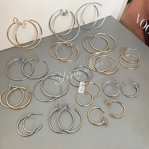 Collection of gold and silver minimalist hoop earrings displayed on a Vogue magazine