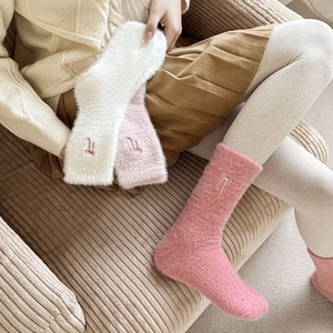 Detail of pink and white plush socks with embroidered bow for cozy winter comfort