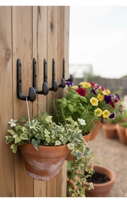 Industrial black cast iron J-shaped hooks mounted on wooden wall for hanging garden flower pots