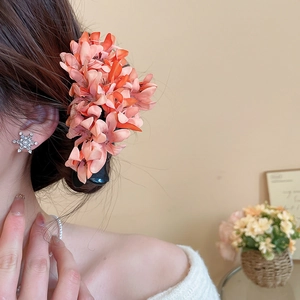 Detail of elegant orange fabric flower hair claw clip with realistic textile texture on a model