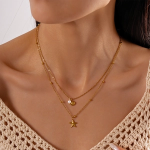 Close-up of double-layered gold necklace with starfish, seashell and pearl charms
