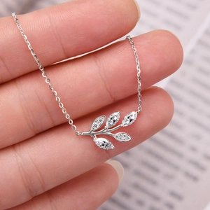 Macro shot of silver olive branch pendant necklace with sparkling moissanite stones