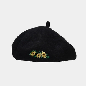 Detailansicht der gelben Sonnenblumen-Stickerei auf schwarzer Wollbaske im Retro-Stil