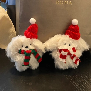 Close-up of white plush bunny rabbits wearing red Christmas hats and striped scarves