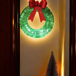 Illuminated Christmas wreath with red bow and LED lights on warm indoor background