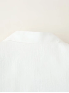 Close-up of white blazer collar showing refined fabric texture and stitching detail