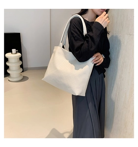 Side view of a white woven tote bag with a wide strap on a model for a daily casual look