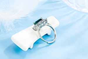 Close-up of silver ring featuring a rectangular emerald gemstone and clear zircon border