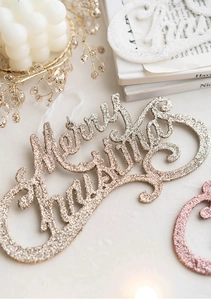 Macro view of champagne gold glittery Merry Christmas lettering decoration for trees