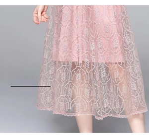 Vue détaillée de la broderie lourde et de la dentelle sur l'ourlet d'une robe rose Qipao