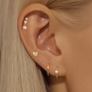 Close-up of gold S925 silver earring set with heart stud and zircon hoop on ear