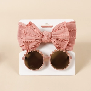 Detailaufnahme von rosa Baby-Stirnband mit Schleife und Sonnenbrille mit Blumendeko