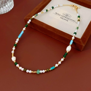 Detail of vintage necklace with white pearls, green stones and gold metal accents