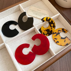 Detailed view of oversized geometric acrylic earrings in black and tortoiseshell finishes