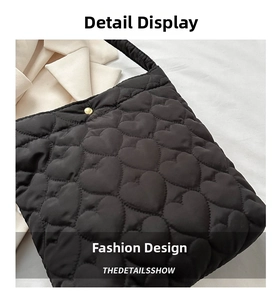 Detail view of heart-shaped quilted pattern and golden snap closure on black padded tote
