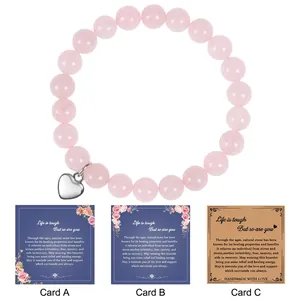 Detail of pink natural stone bracelet with heart pendant and friendship greeting cards